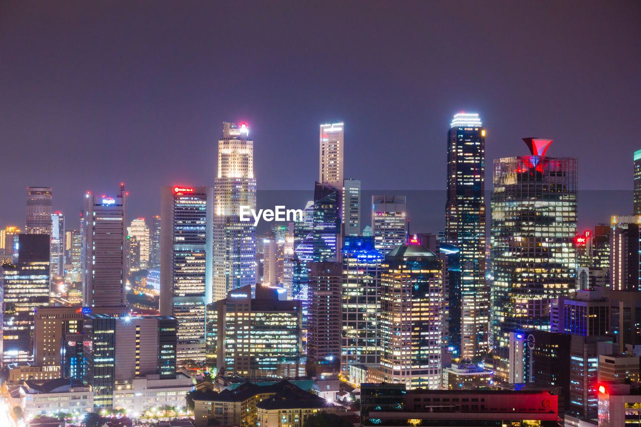 Illuminated buildings in city against sky at night