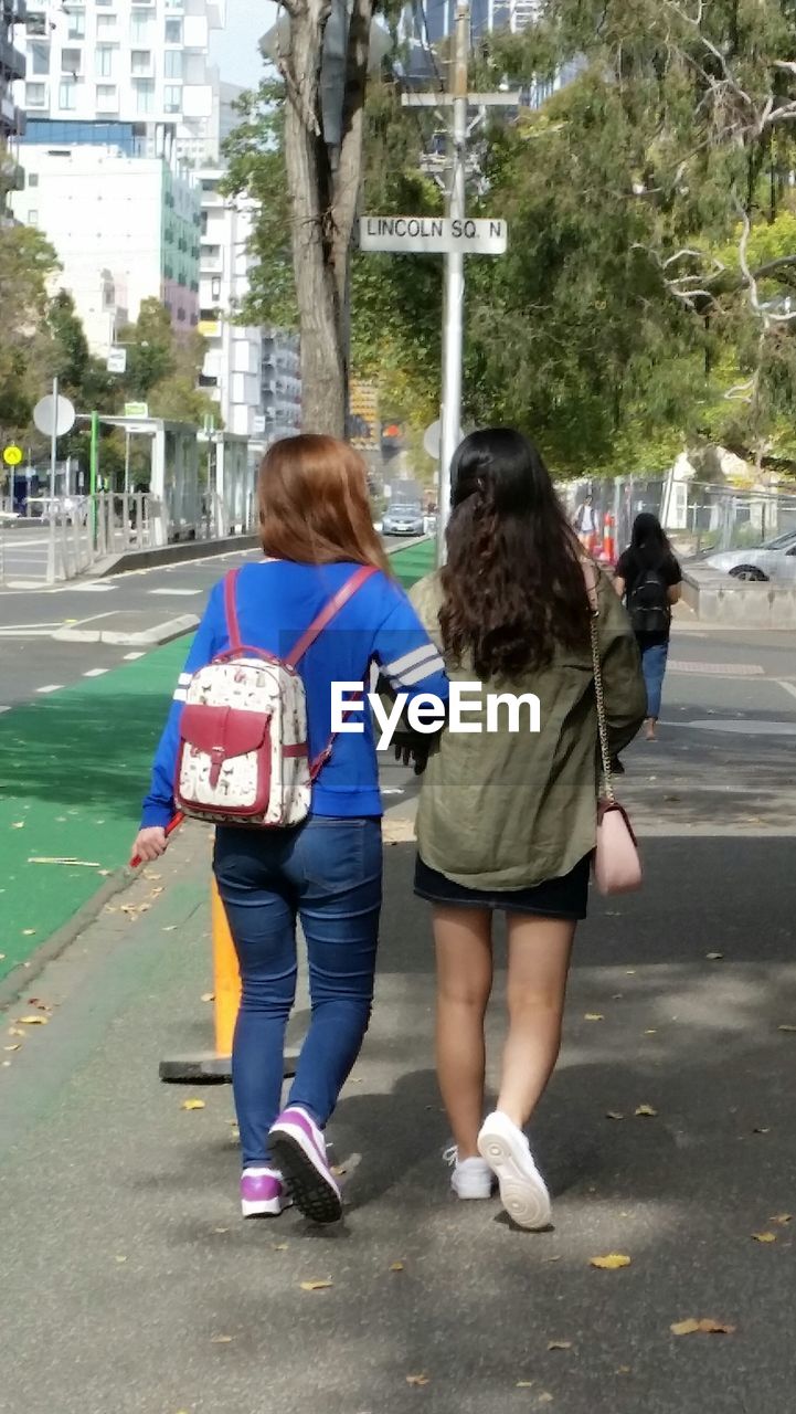 REAR VIEW OF WOMAN WALKING ON STREET