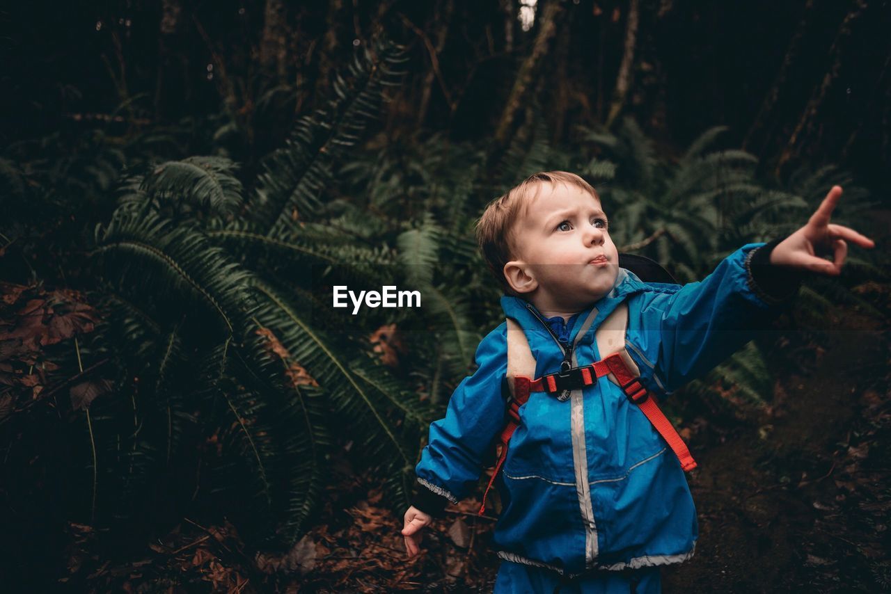 Boy standing against tree