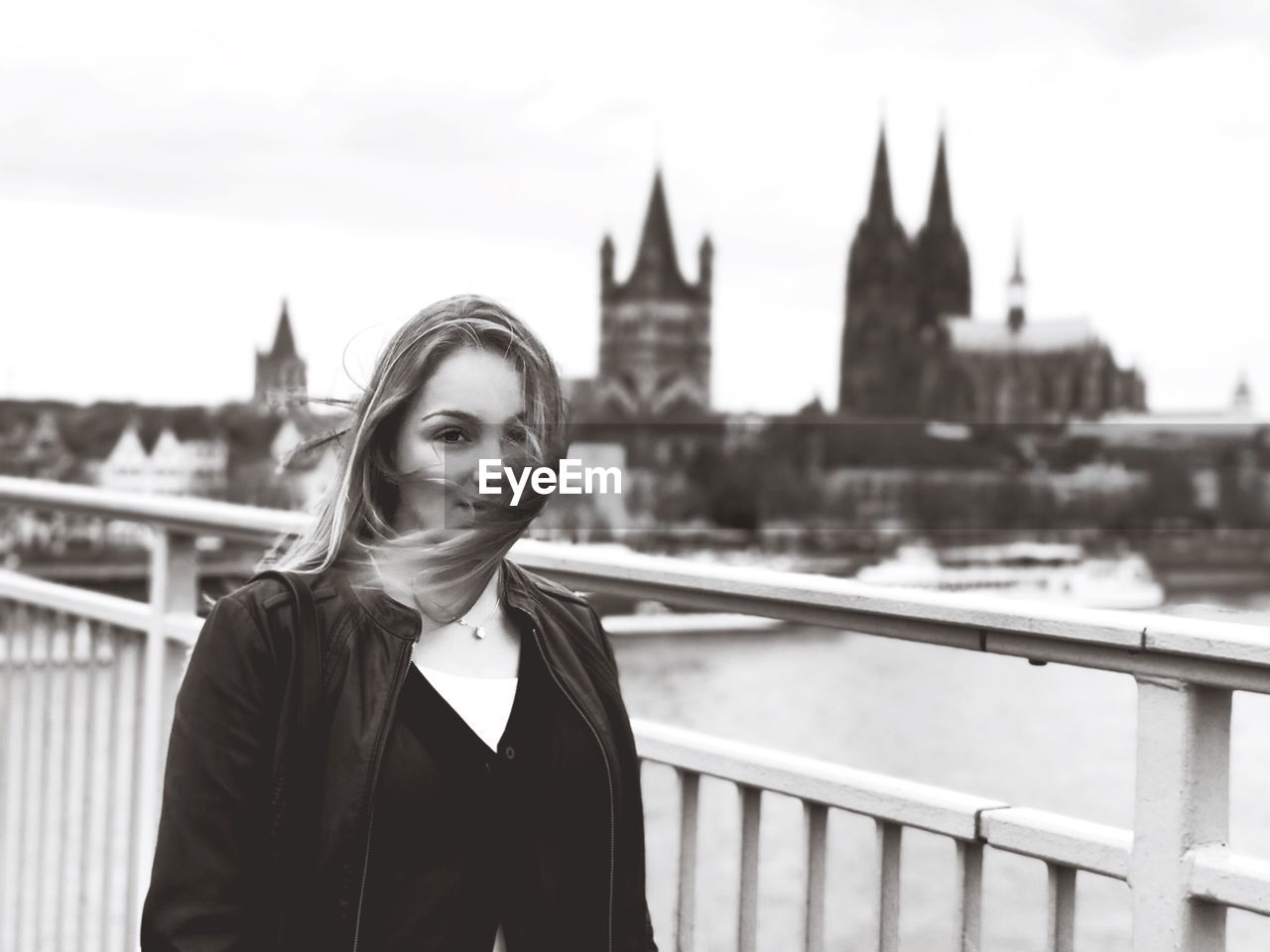 Portrait of woman standing by railing against cityscape