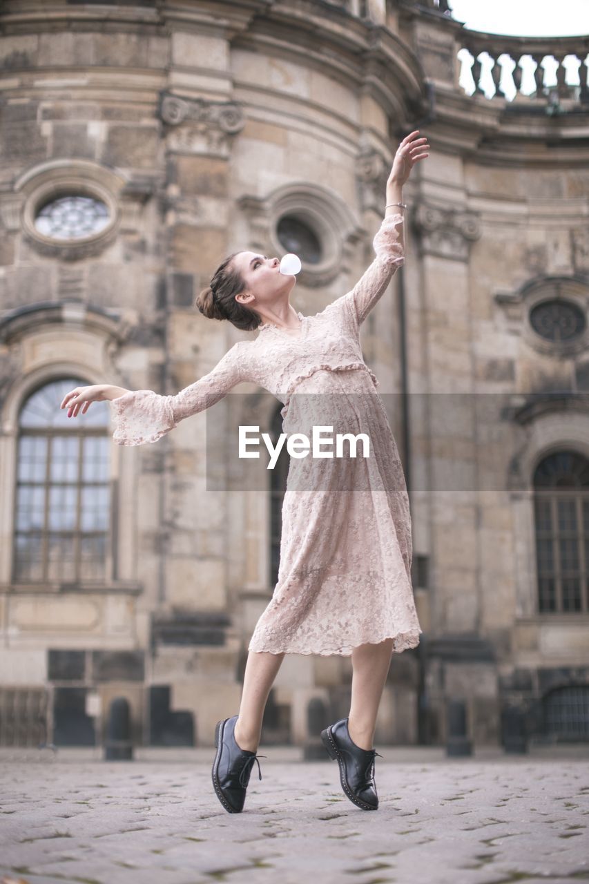 Full length of woman with arms raised in city