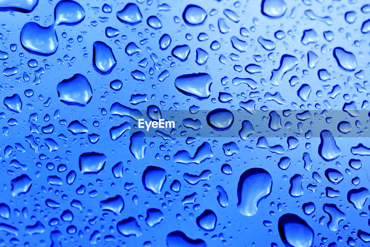 FULL FRAME SHOT OF RAINDROPS ON BLUE WATER DROPS