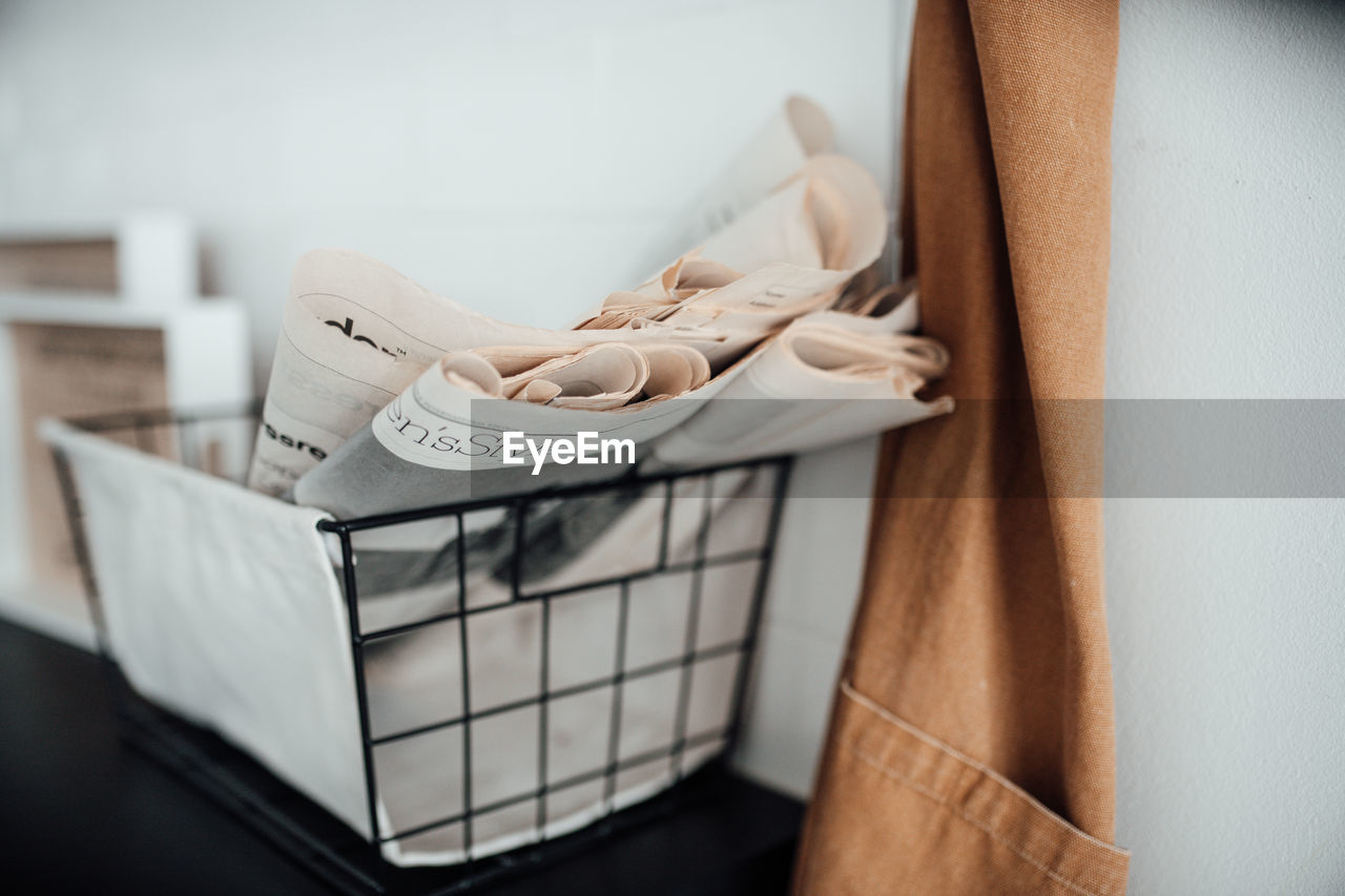 Close-up of newspaper in basket by wall at home