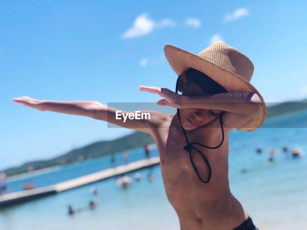 Shirtless boy gesturing while standing at beach during summer