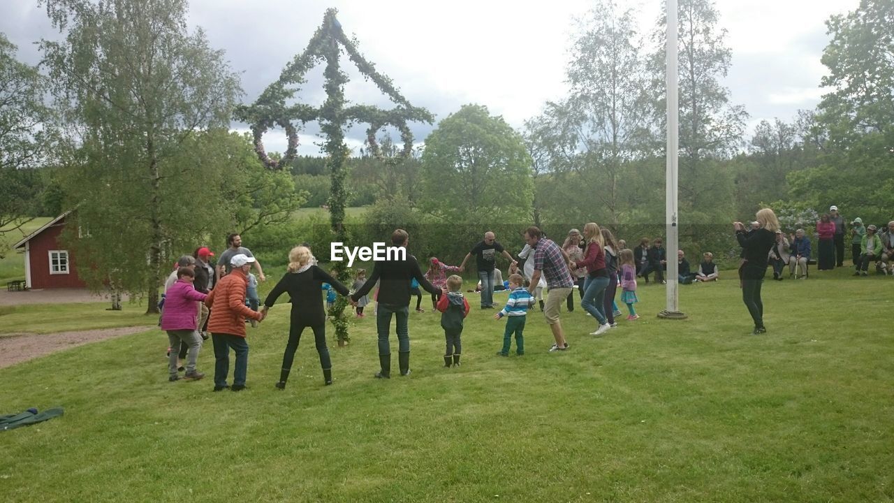 PEOPLE STANDING ON GRASS AGAINST TREES