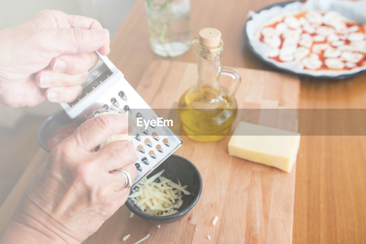 Close-up of woman grating cheese on table