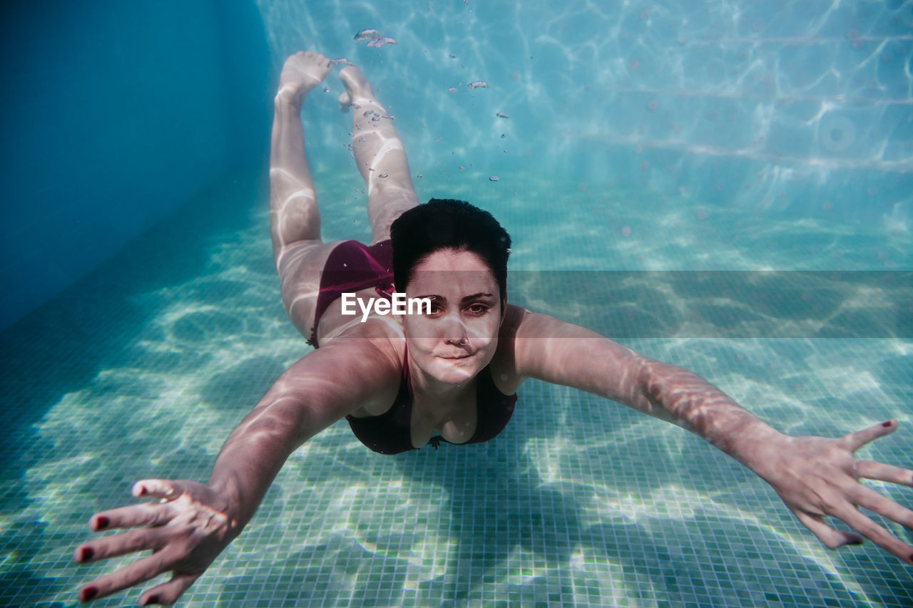 Portrait of woman swimming underwater in pool