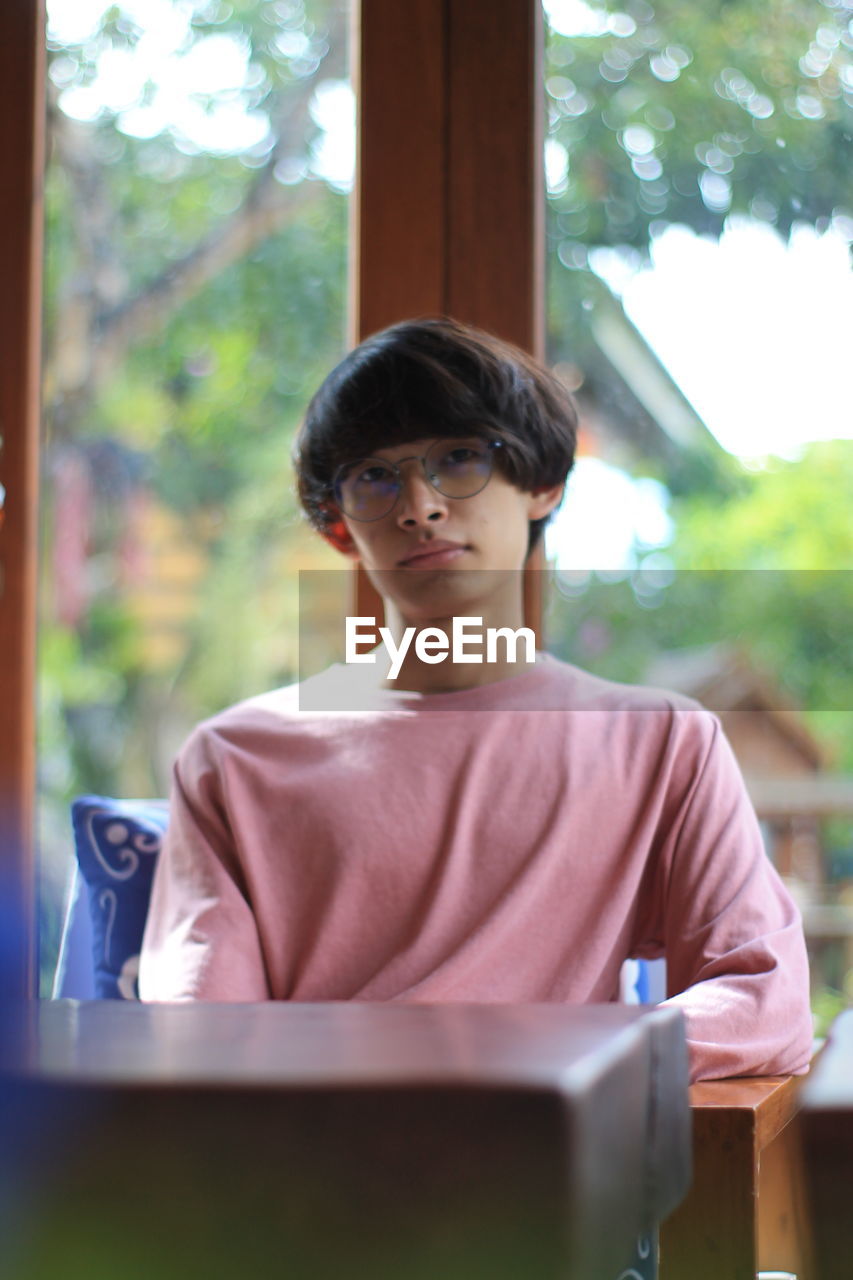 PORTRAIT OF A BOY LOOKING THROUGH WINDOW