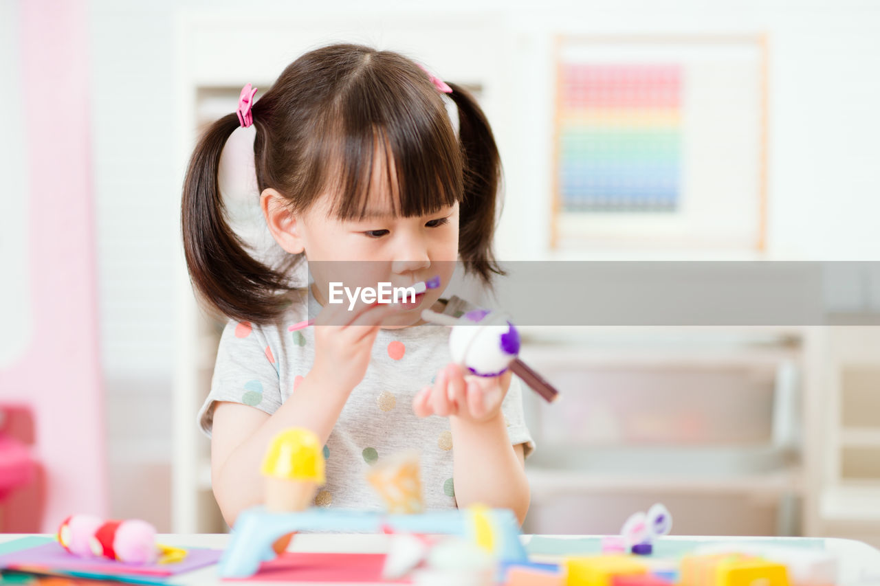 Young girl decorating hand made craft for homeschooling