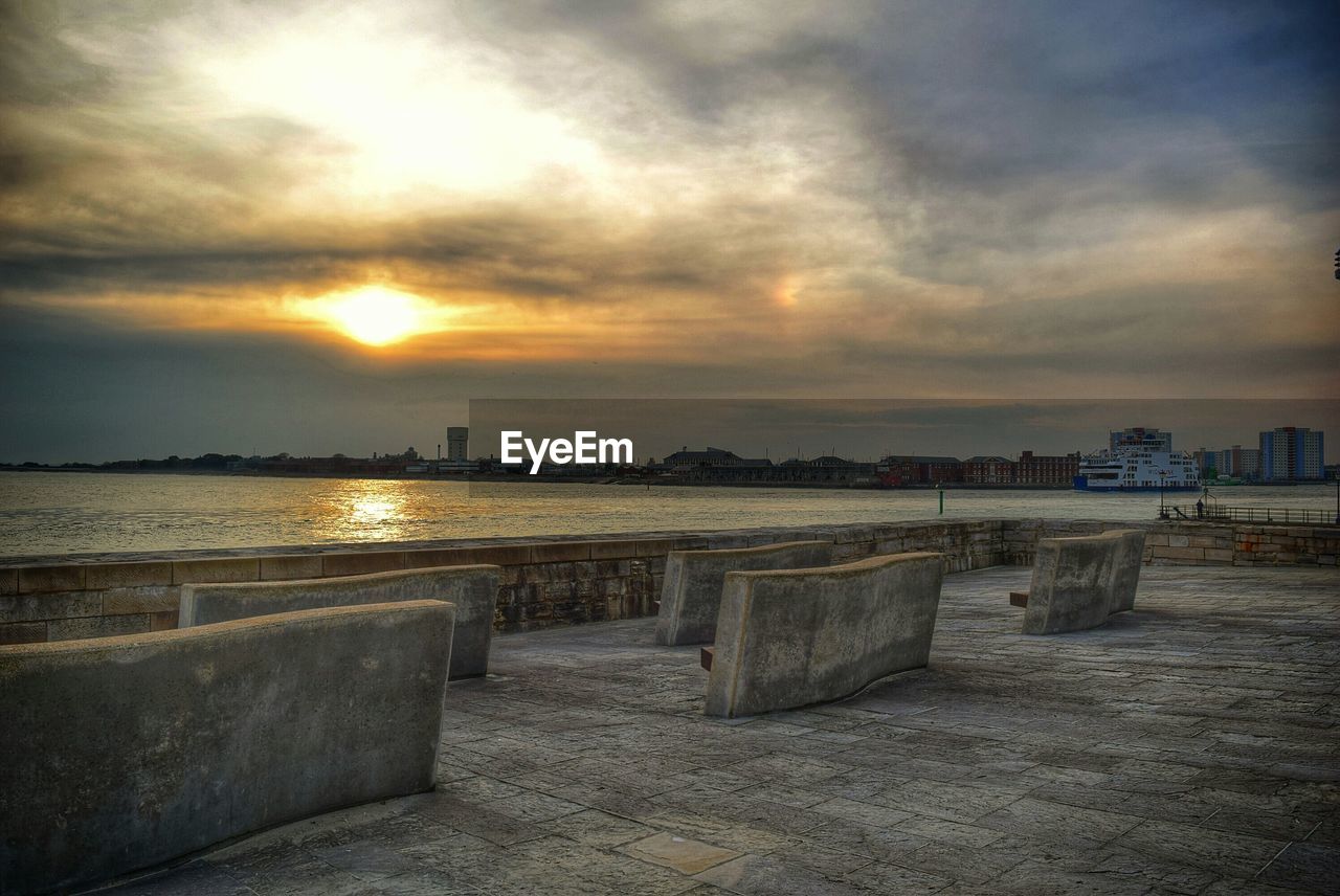 Benches at observation point in front of sea during sunset