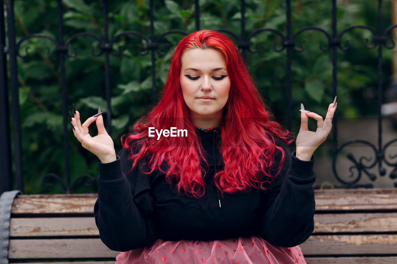 PORTRAIT OF BEAUTIFUL YOUNG WOMAN USING PHONE WHILE STANDING ON CAMERA