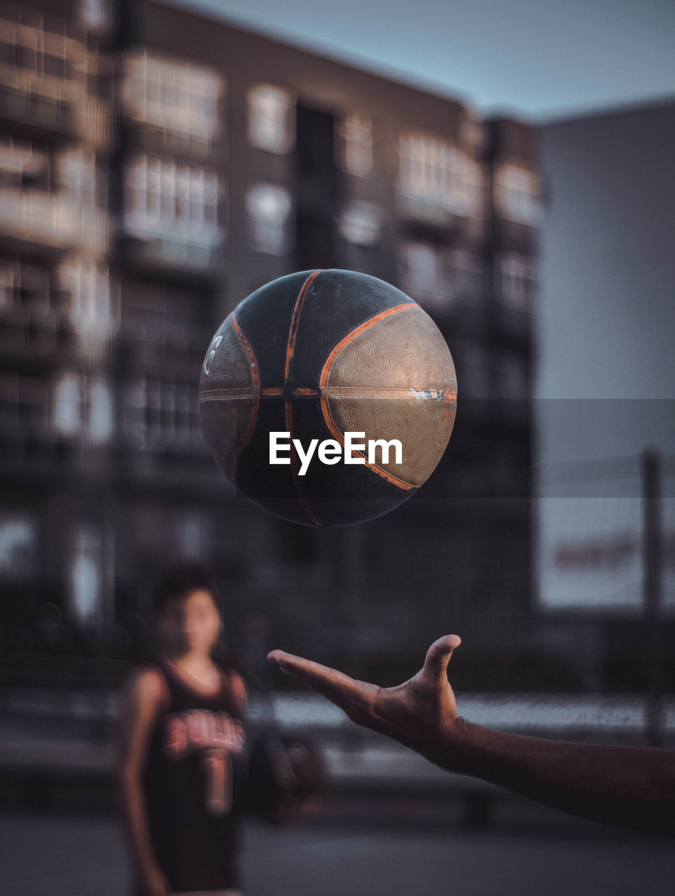 Cropped image of man with ball against building in city