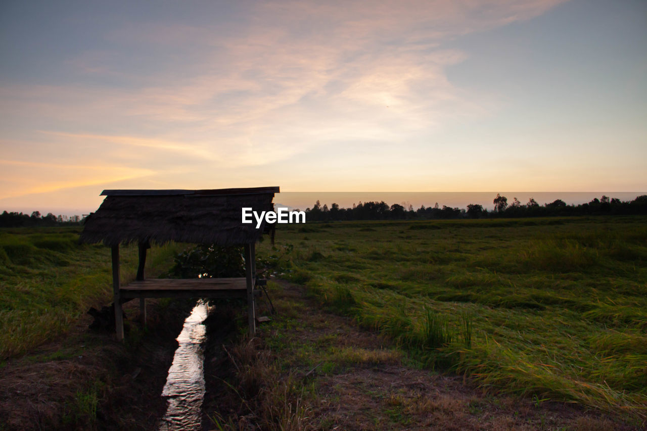 Built structure on field against sky during sunset