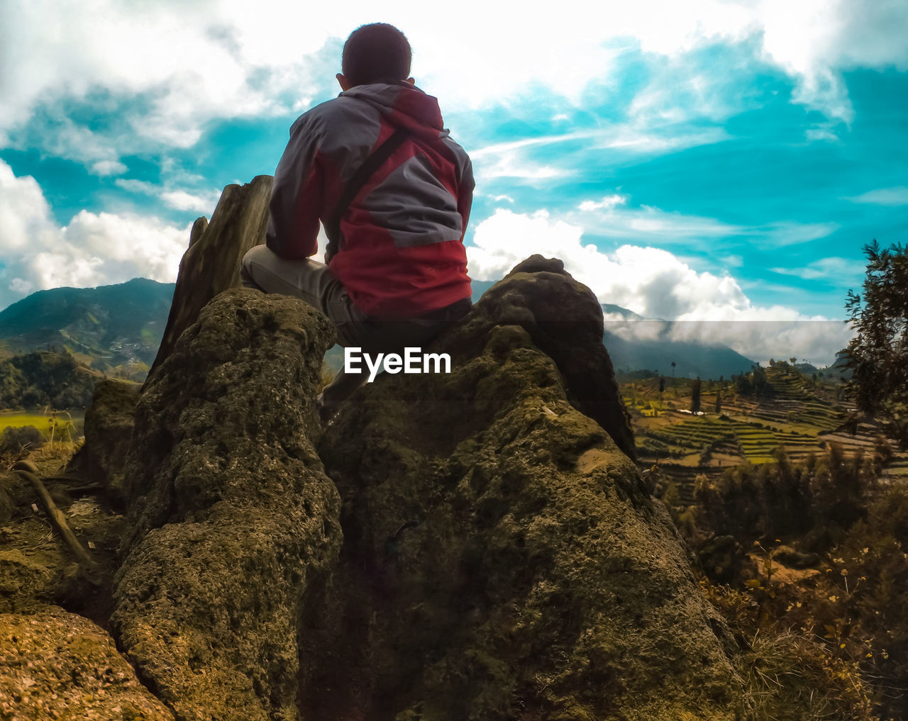 LOW ANGLE VIEW OF MAN STANDING ON MOUNTAIN AGAINST SKY