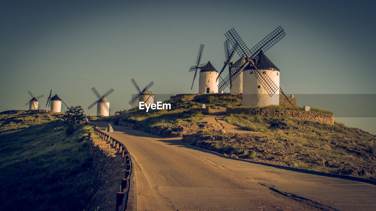 Traditional windmill by road against clear sky