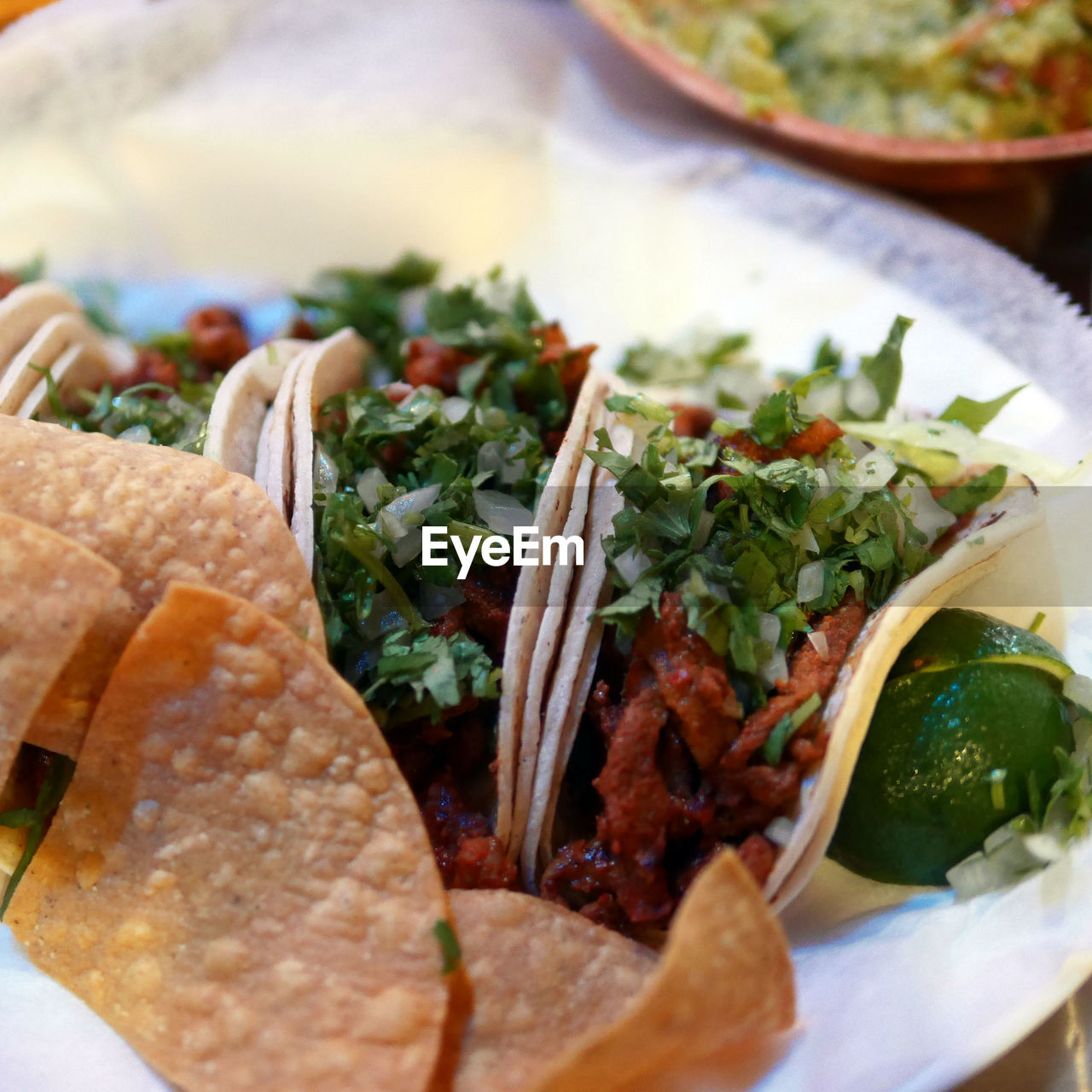 Close-up of served tortilla chips with wrap sandwich in plate