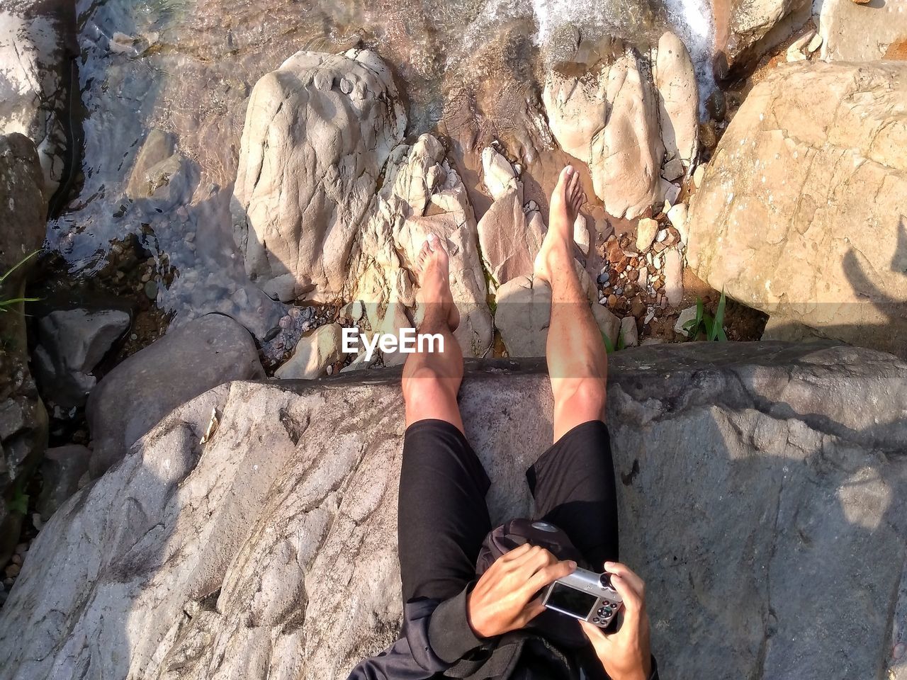 Low section of man photographing with camera on cliff