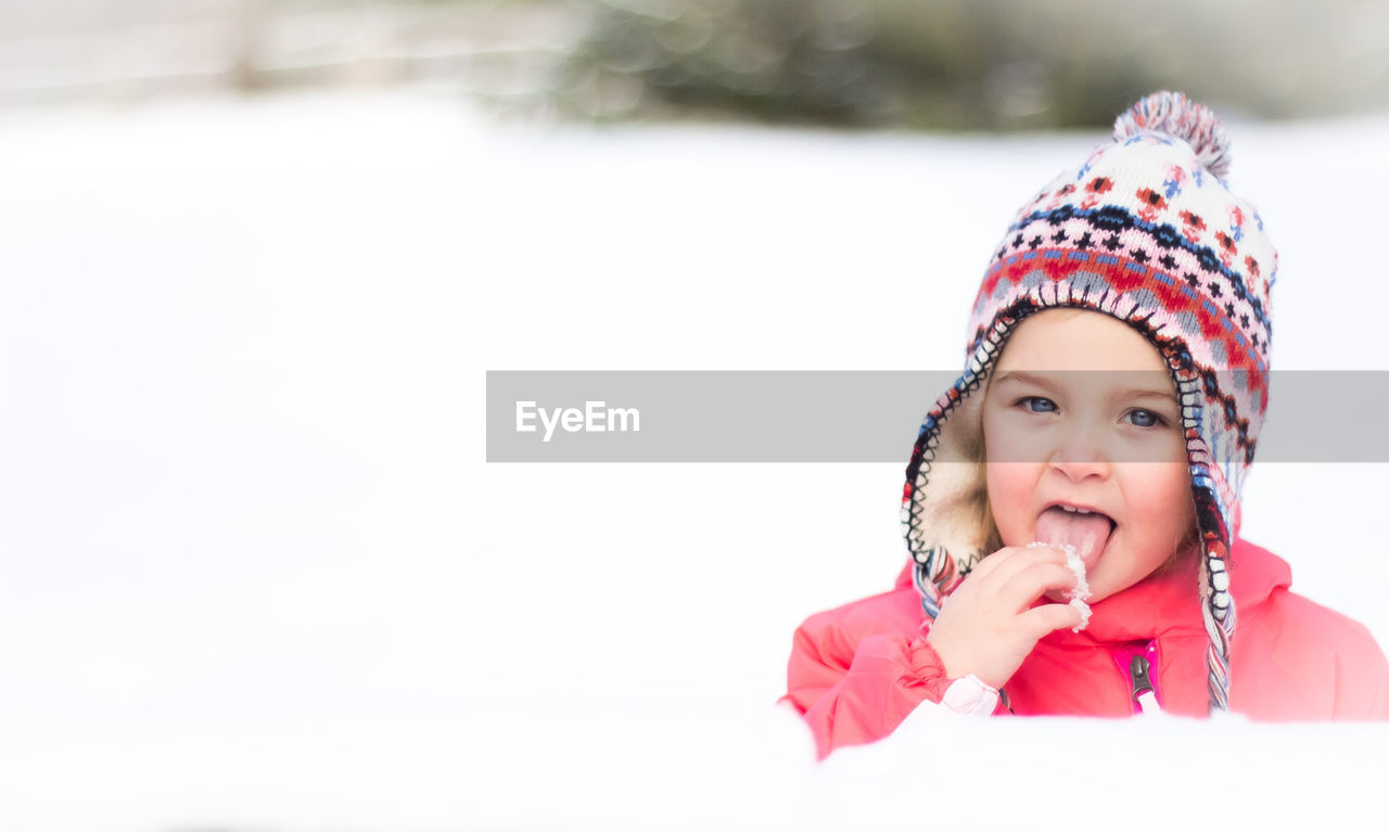 Close-up portrait of girl eating snow outdoors