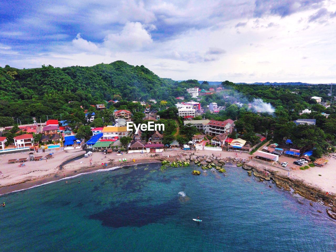 HIGH ANGLE VIEW OF TOWN BY SEA AGAINST CLOUDY SKY