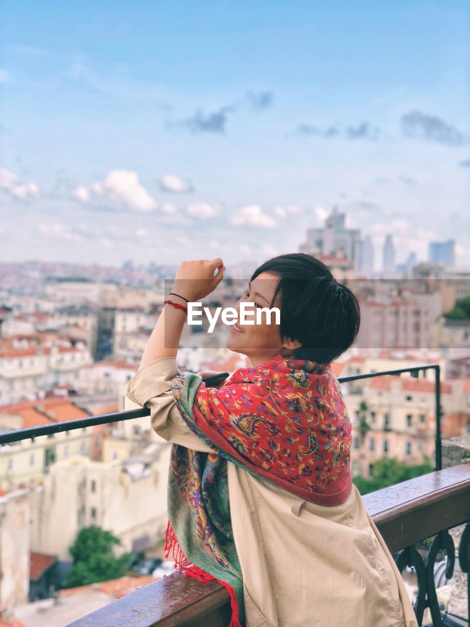 Smiling young woman looking at city against sky