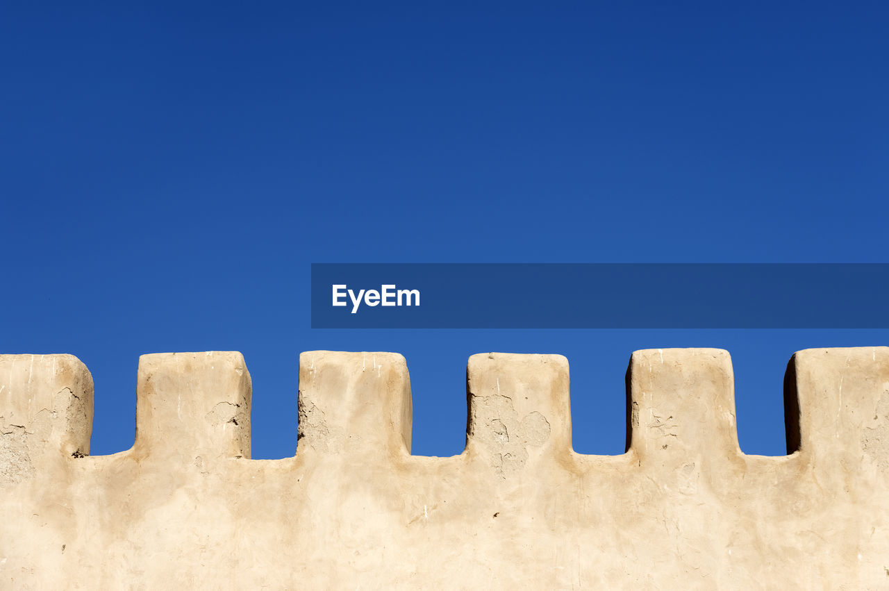 Close-up of white wall against blue sky