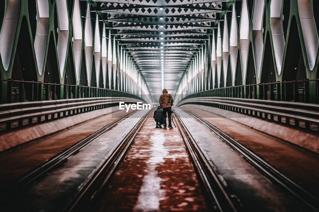 Rear view of people walking on railway bridge