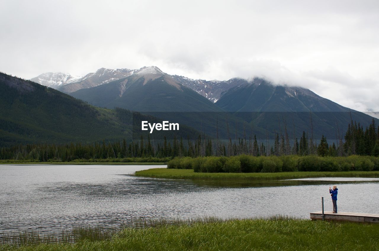 Scenic view of lake by mountains against sky