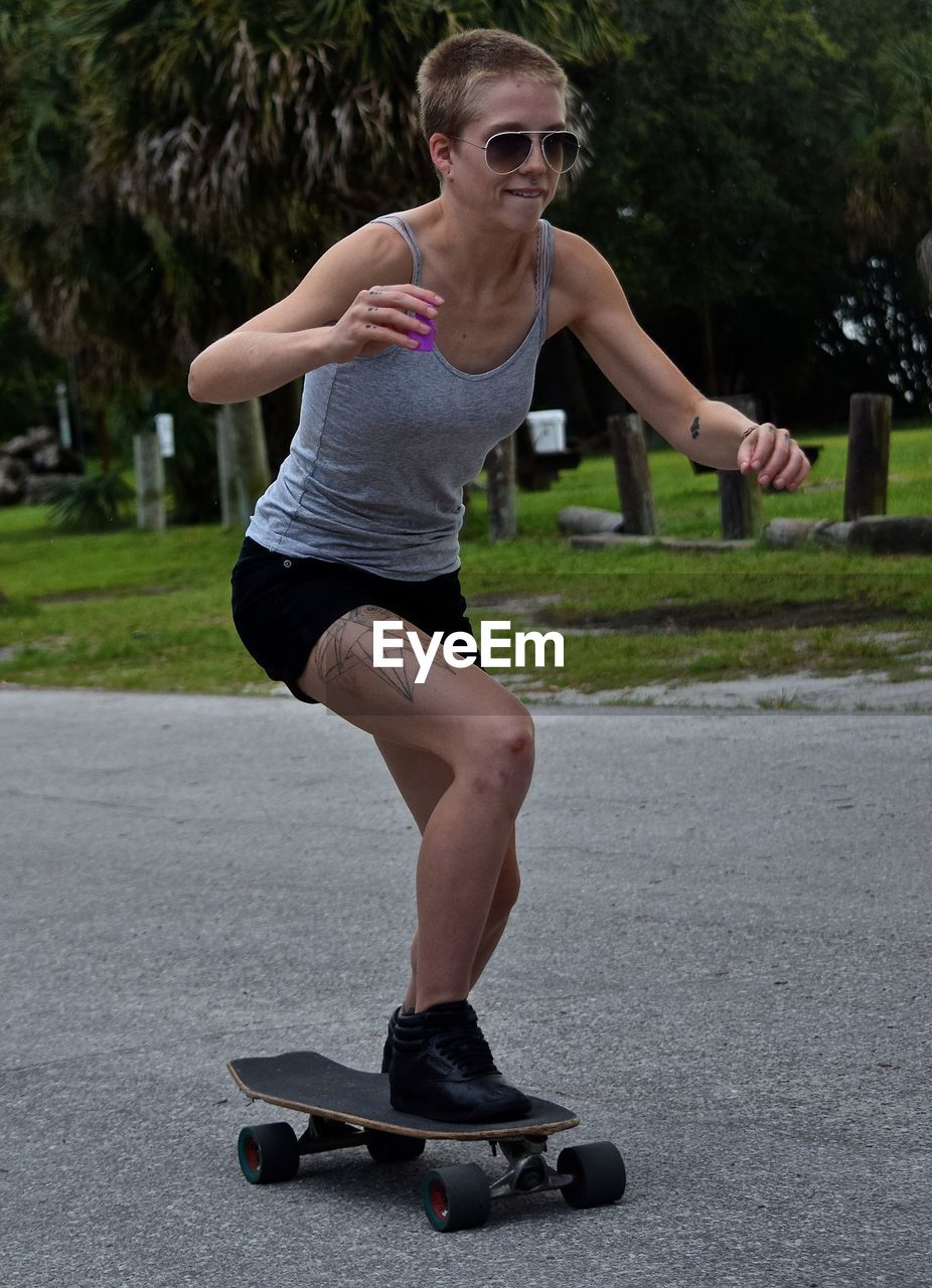 Full length of woman skateboarding on road