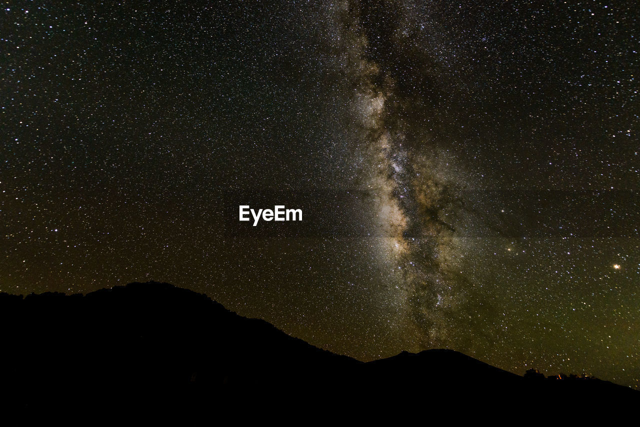 Low angle view of silhouette mountain against star field at night