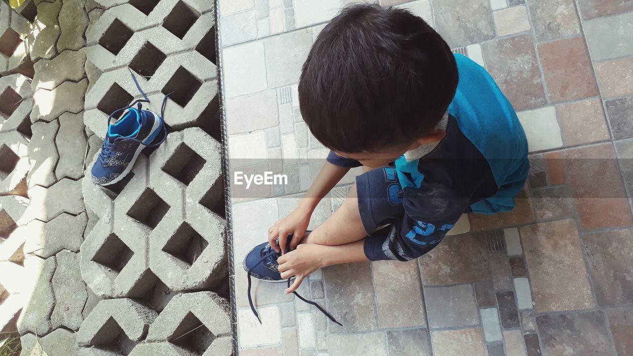 High angle view of boy tying shoelace at home