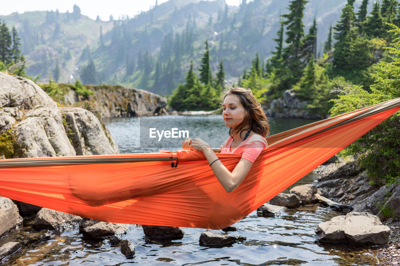 Woman is relaxing in a hammock at the alpine lake on local vacation