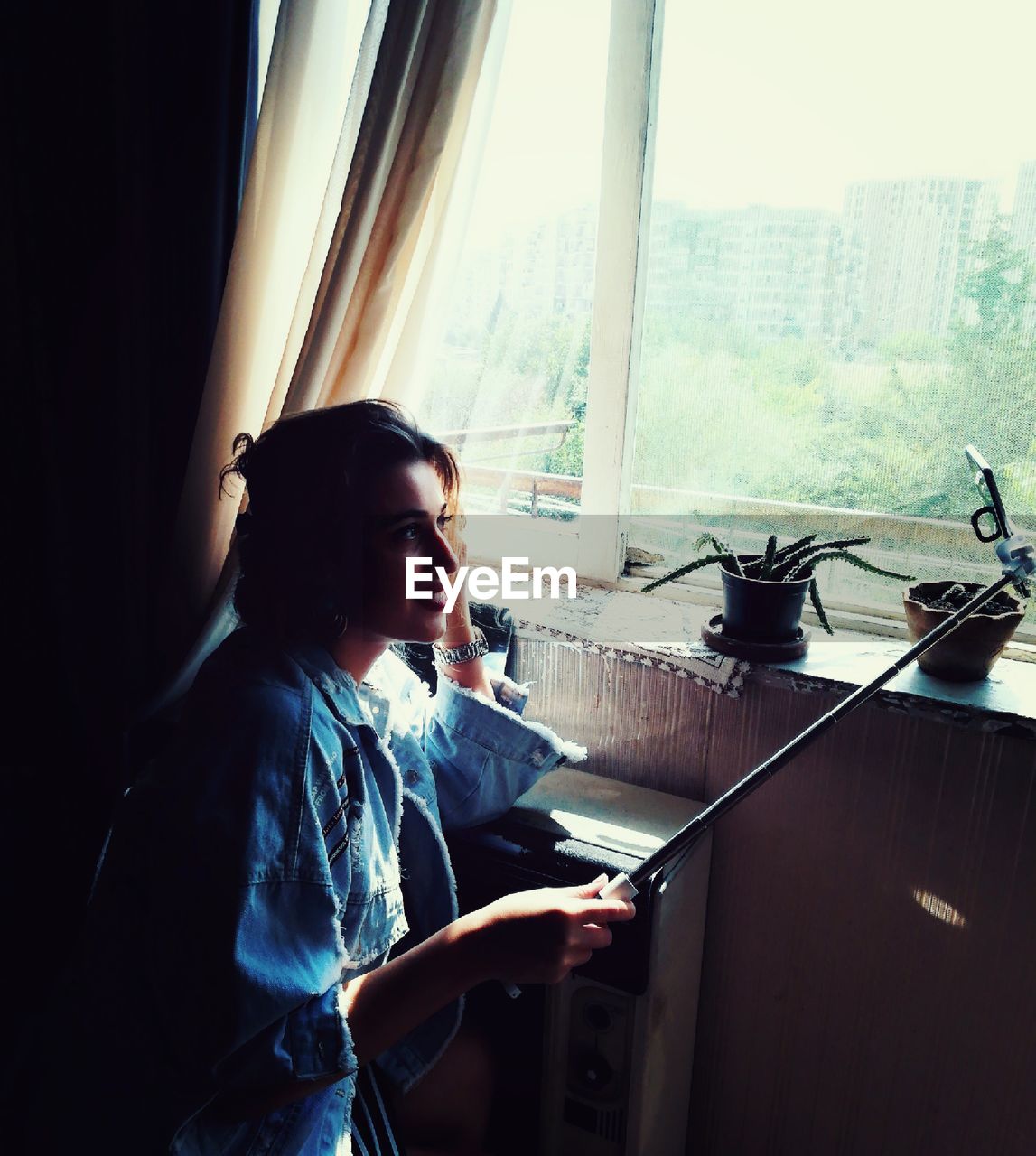 Woman taking selfie by window at home