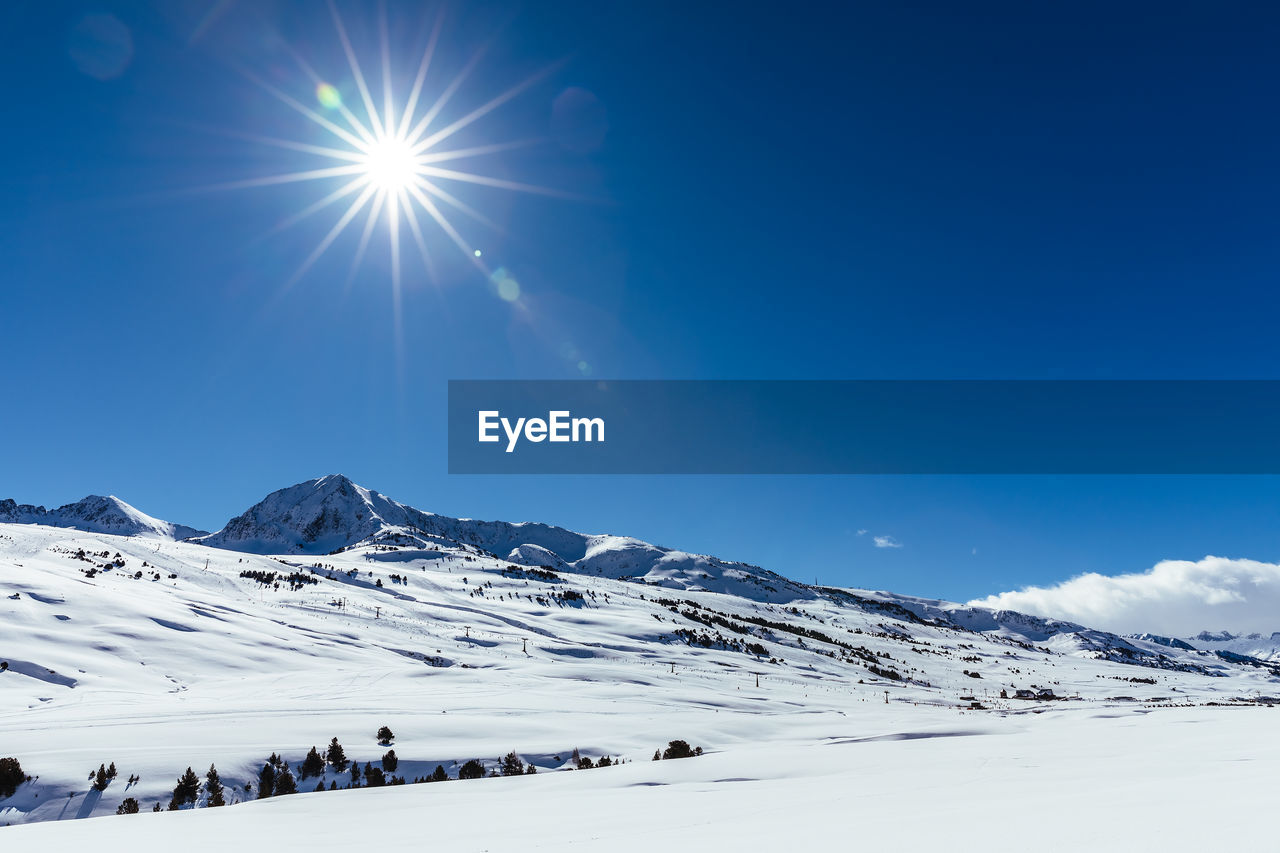 Scenic view of snowcapped mountains against blue sky