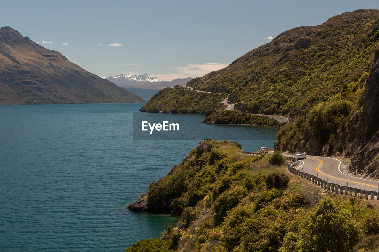 Road on mountain by lake against sky