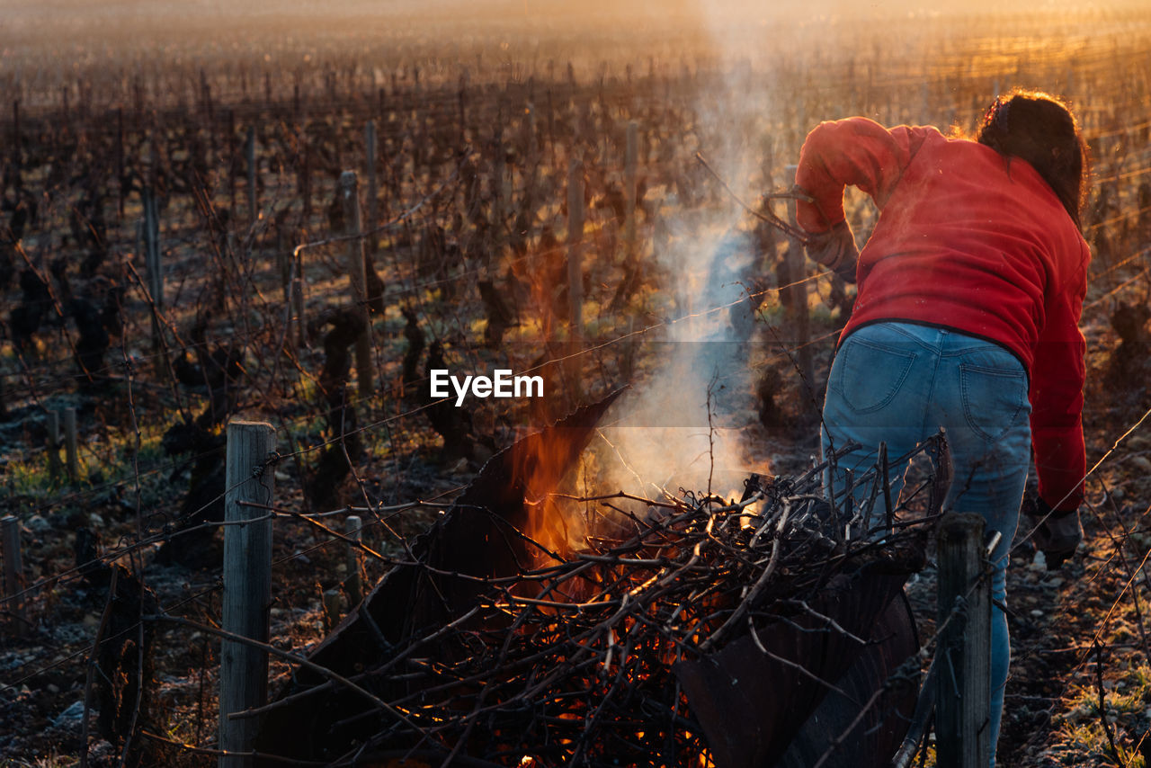 Rear view of woman standing by bonfire