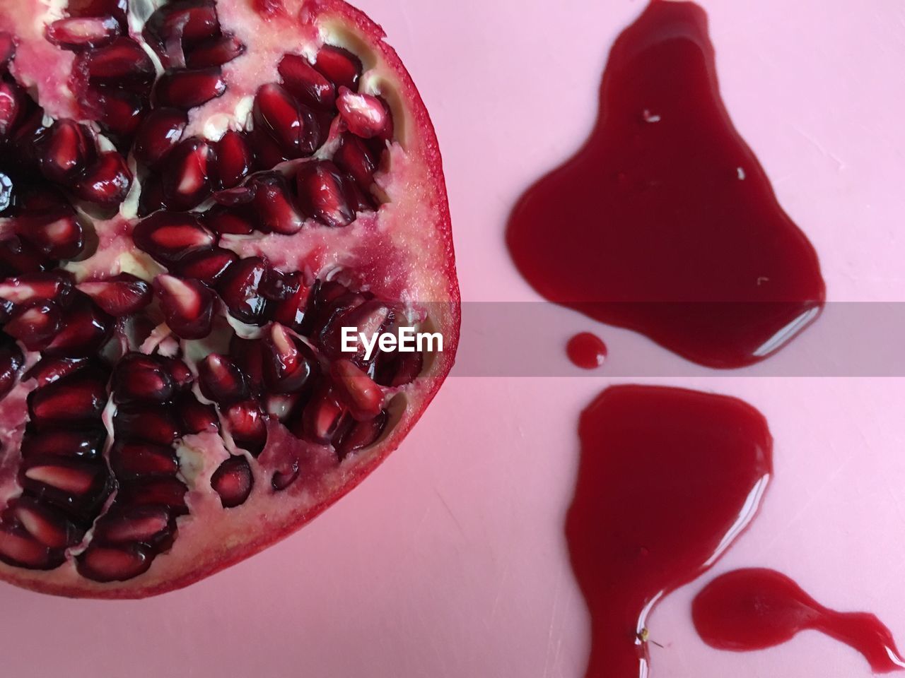 Directly above shot of halved pomegranate on pink table