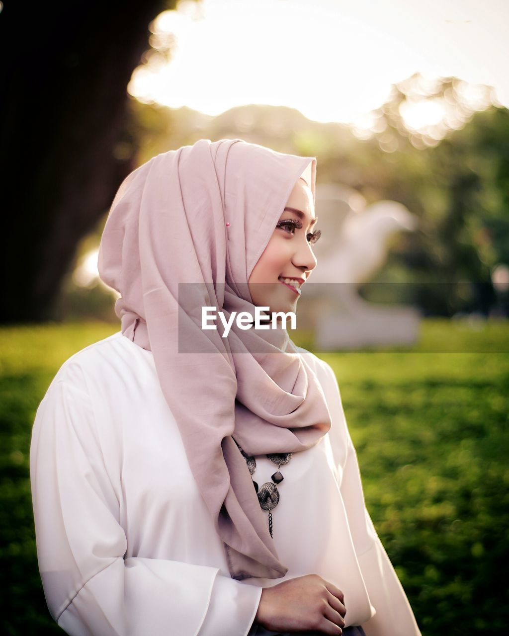 Smiling beautiful woman wearing hijab looking away at park
