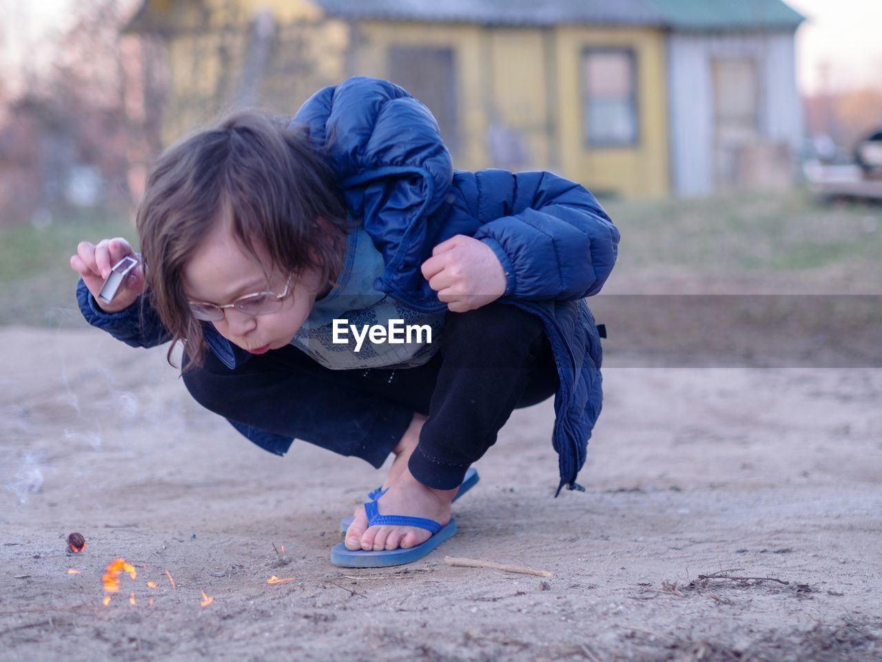 Full length of boy blowing while crouching on land