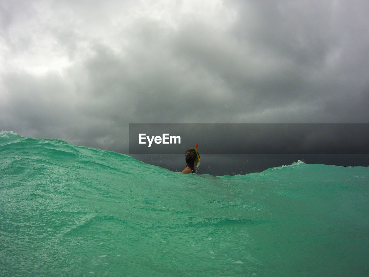 Woman snorkeling in sea against storm clouds