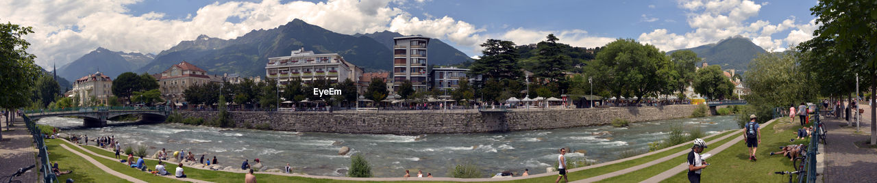 PANORAMIC VIEW OF PEOPLE ON STREET BY BUILDINGS IN CITY