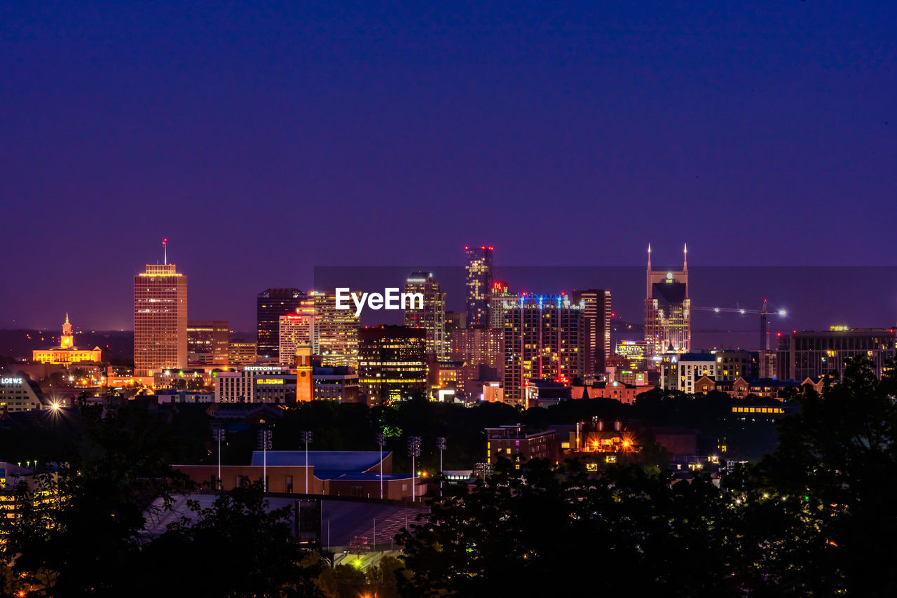 Illuminated buildings against clear sky at night