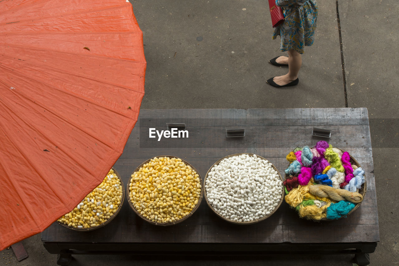 Low section of woman standing by silkworm cocoons on market stall