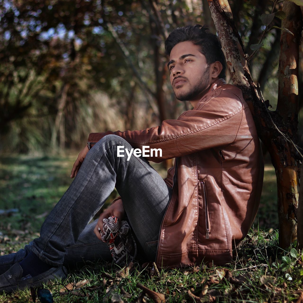 Side view of young man sitting on field