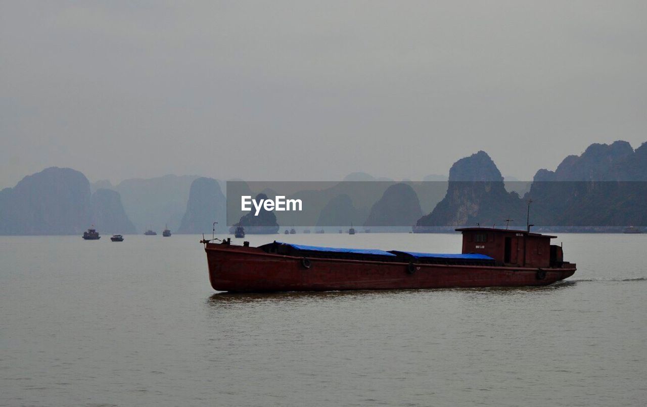 NAUTICAL VESSEL ON SEA AGAINST MOUNTAINS