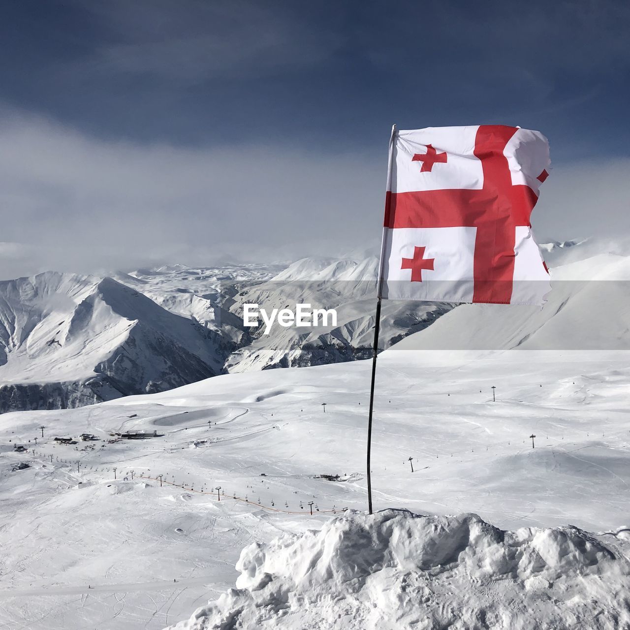 FLAG ON SNOW COVERED MOUNTAIN AGAINST SKY