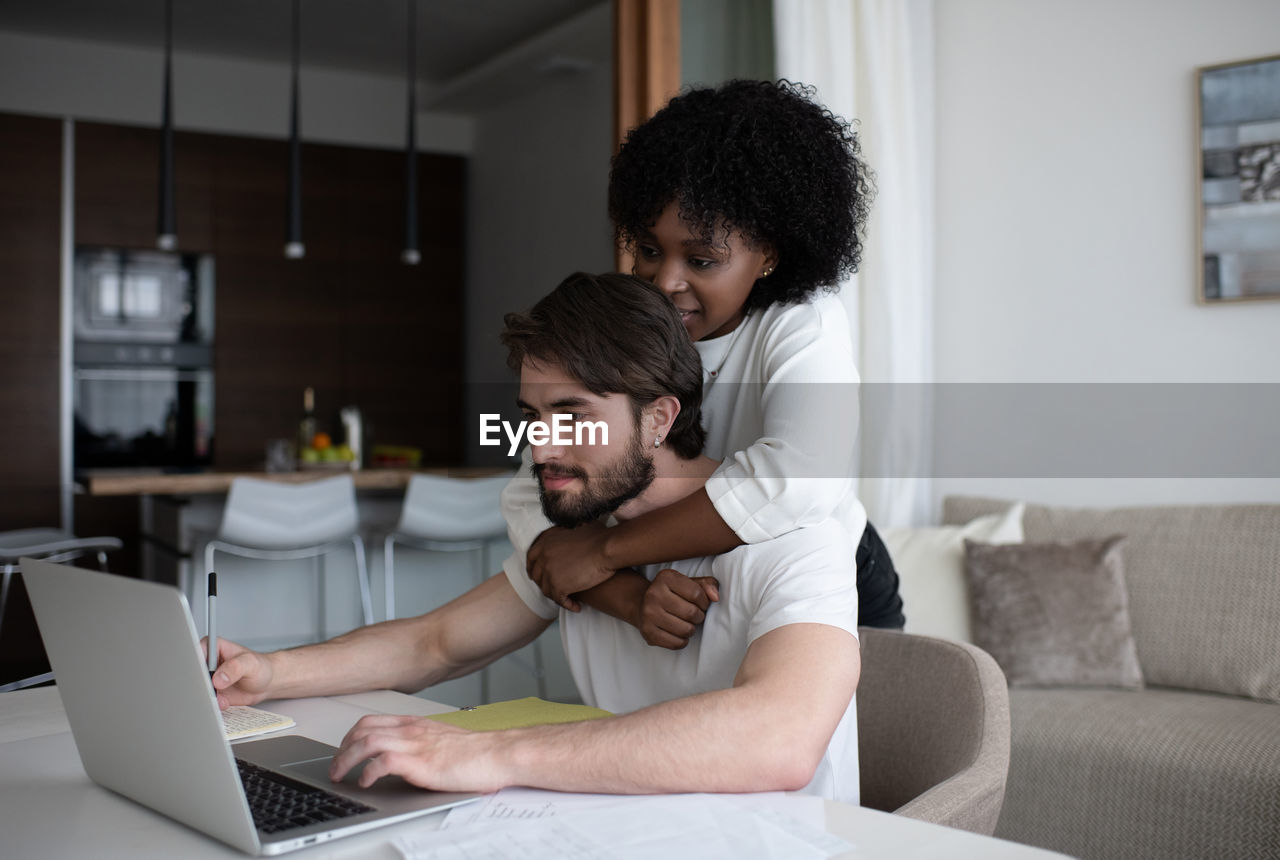 Black woman helping man with remote job