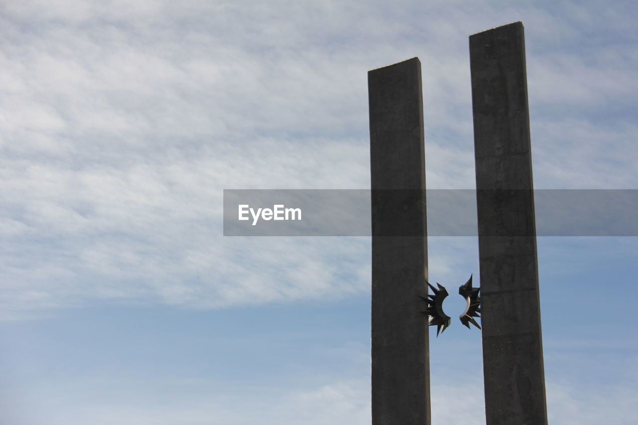 LOW ANGLE VIEW OF POLES AGAINST CLOUDY SKY