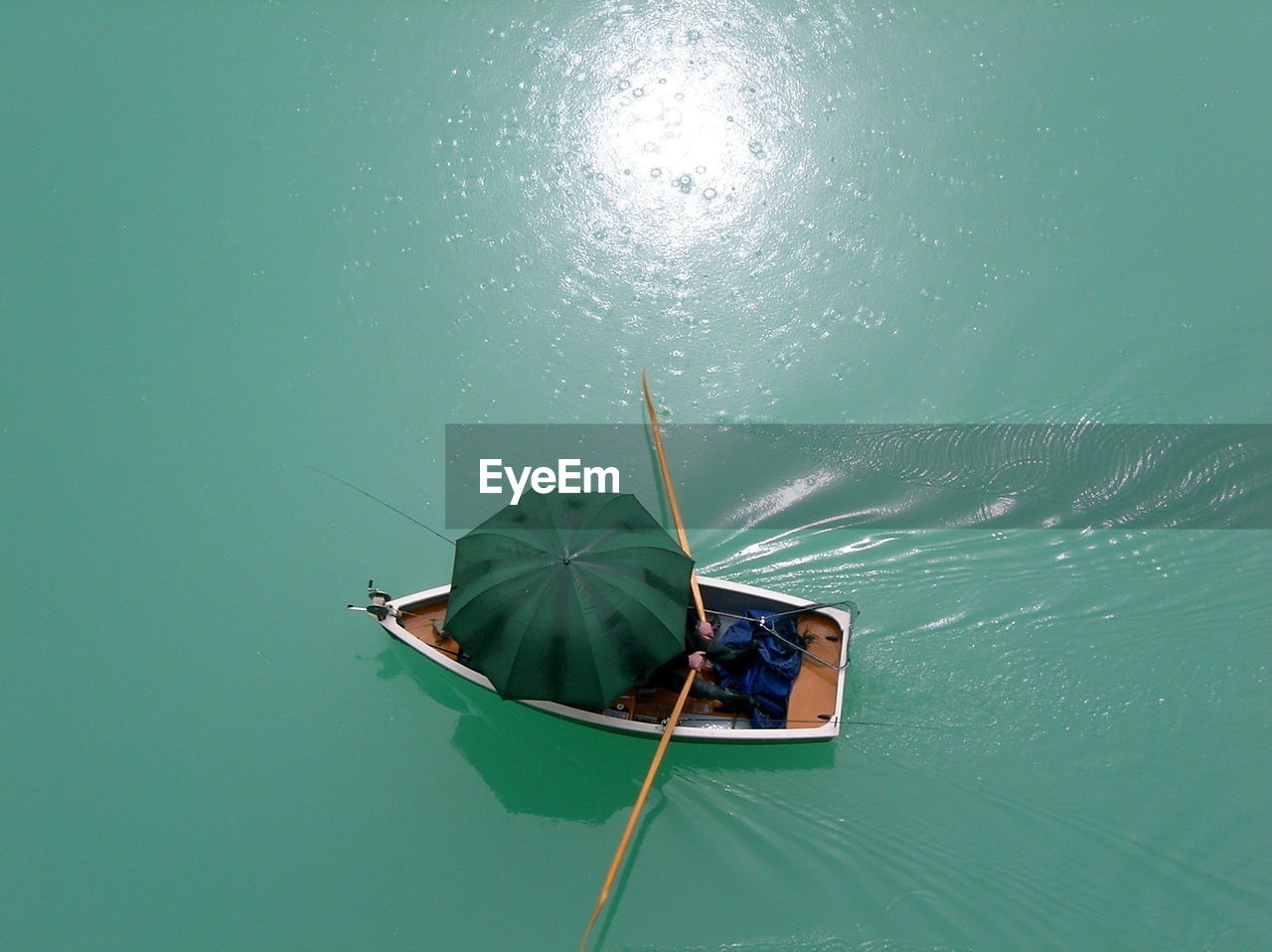High angle view of person covered with umbrella sailing boat in lake