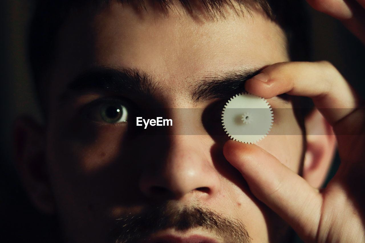 Close-up of young man's eyes holding a screw