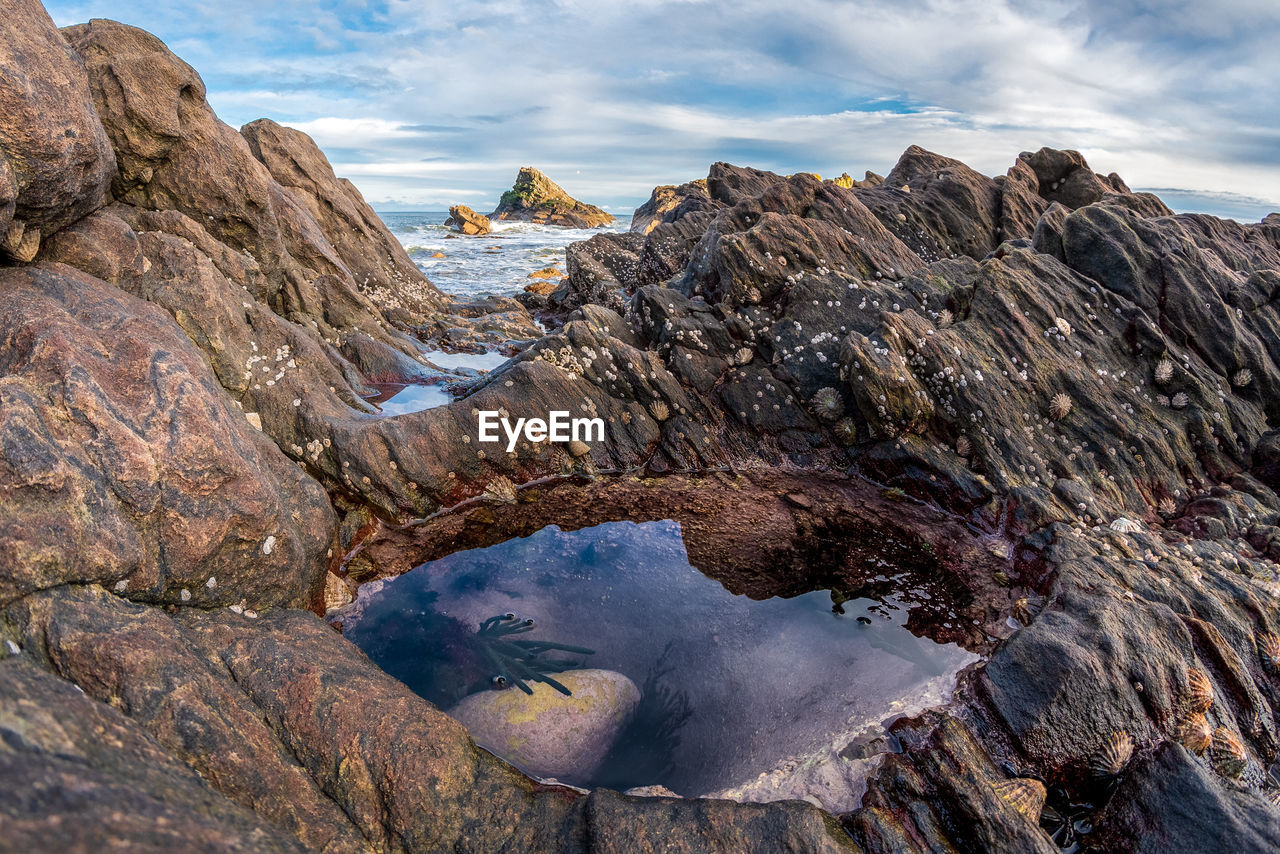 Rock formations on shore against sky